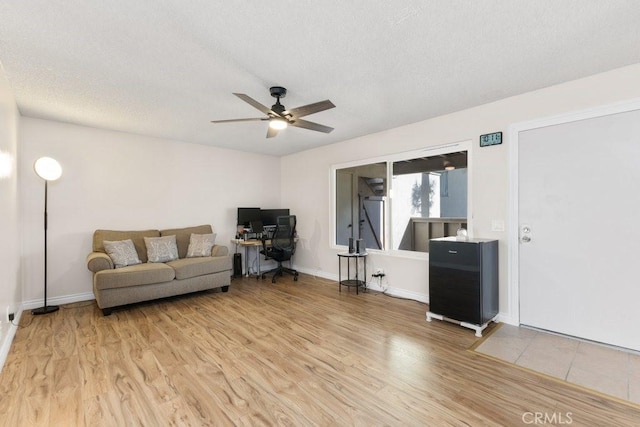 living room with a textured ceiling, light wood-type flooring, and ceiling fan