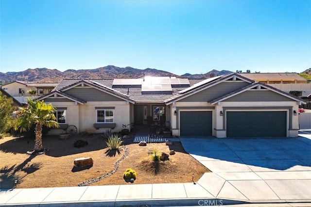 view of front of home with a mountain view, solar panels, and a garage