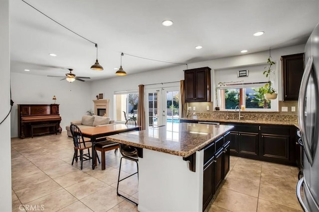 kitchen featuring stainless steel refrigerator, ceiling fan, a center island, french doors, and a breakfast bar