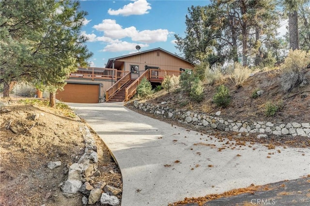 view of front of house with driveway, stairs, a garage, and a deck