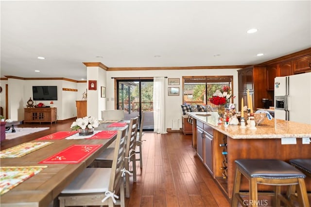 kitchen featuring light stone counters, recessed lighting, crown molding, and dark wood finished floors