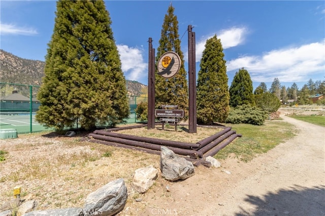 surrounding community with a tennis court, a mountain view, and fence