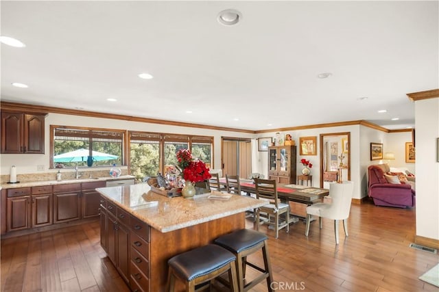 kitchen with visible vents, a sink, a center island, and wood-type flooring