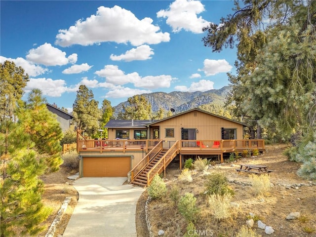 view of front of house featuring driveway, stairway, a deck with mountain view, and an attached garage