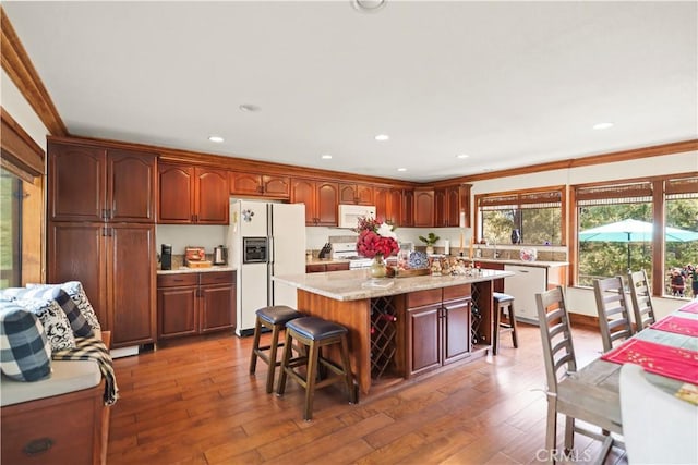 kitchen with plenty of natural light, white appliances, a breakfast bar area, and light wood-style flooring