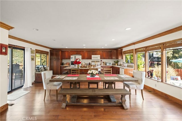 dining room featuring baseboards, ornamental molding, wood finished floors, and recessed lighting