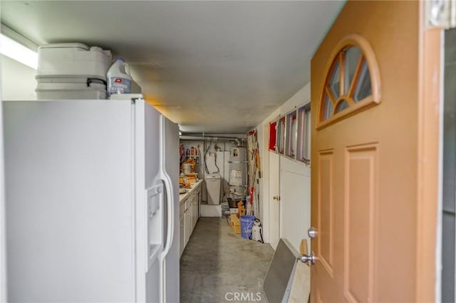 finished below grade area featuring white refrigerator with ice dispenser, secured water heater, and washing machine and clothes dryer