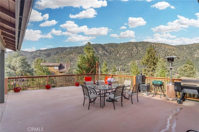 view of patio with area for grilling, outdoor dining area, and a mountain view