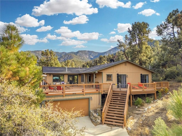 view of front of property with driveway, stairway, a deck with mountain view, and an attached garage