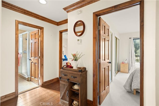 hall with baseboards, light wood-style floors, and ornamental molding