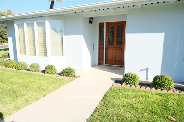 view of exterior entry featuring a lawn