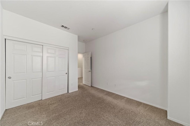 unfurnished bedroom with baseboards, carpet, visible vents, and a closet