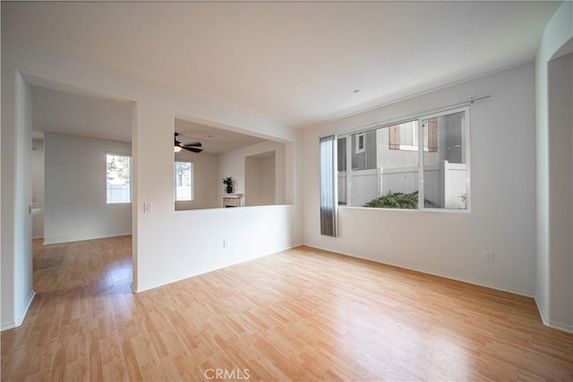 empty room featuring ceiling fan, light wood finished floors, and baseboards