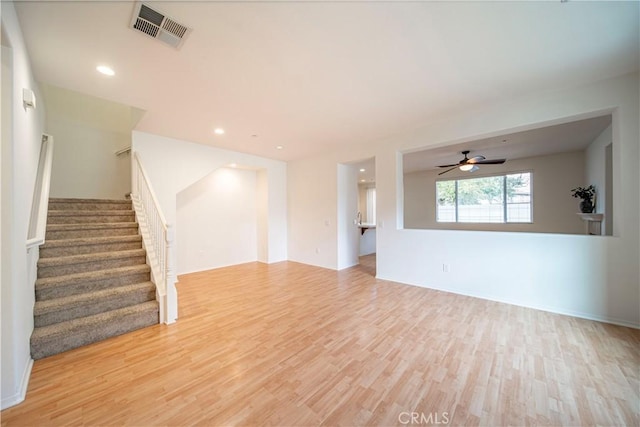 unfurnished living room featuring visible vents, a ceiling fan, stairs, light wood-style floors, and recessed lighting