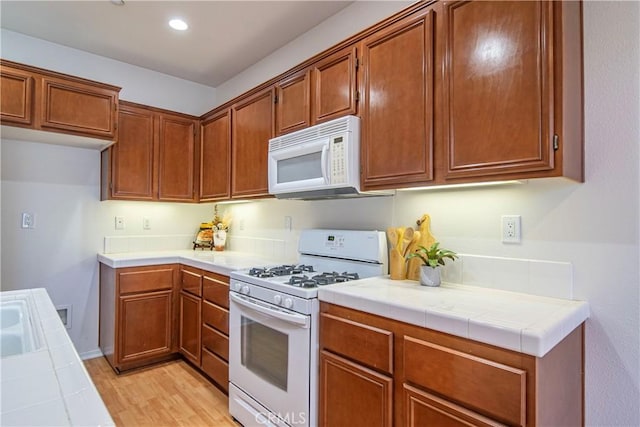 kitchen with white appliances, tile counters, and brown cabinetry