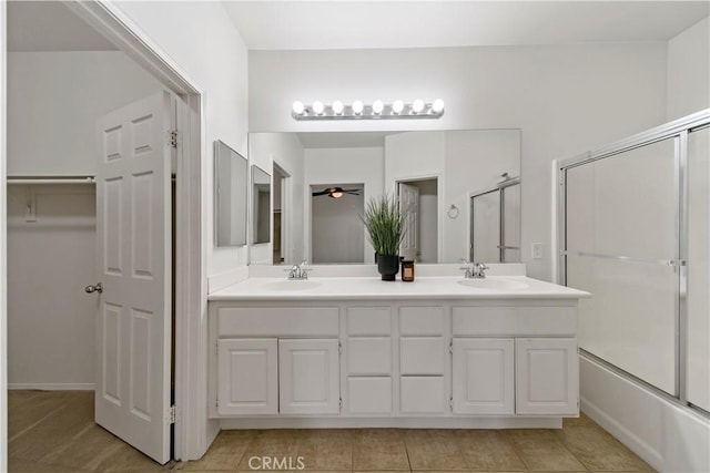 full bath with bath / shower combo with glass door, double vanity, a sink, and a ceiling fan