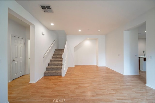 unfurnished room with recessed lighting, visible vents, baseboards, stairs, and light wood finished floors