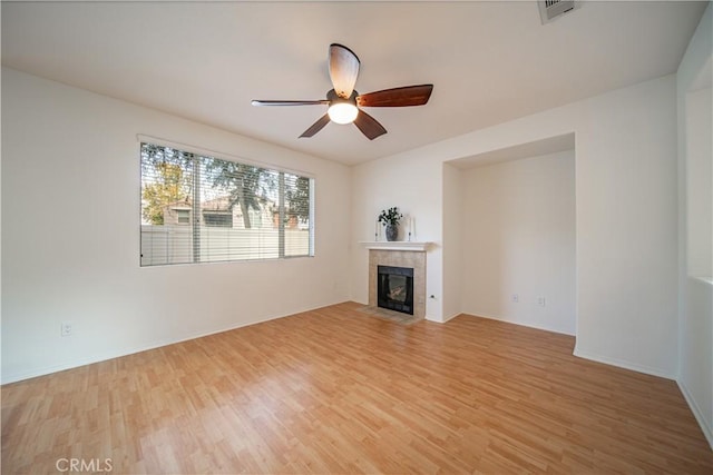 unfurnished living room with a ceiling fan, baseboards, visible vents, light wood-style floors, and a tiled fireplace