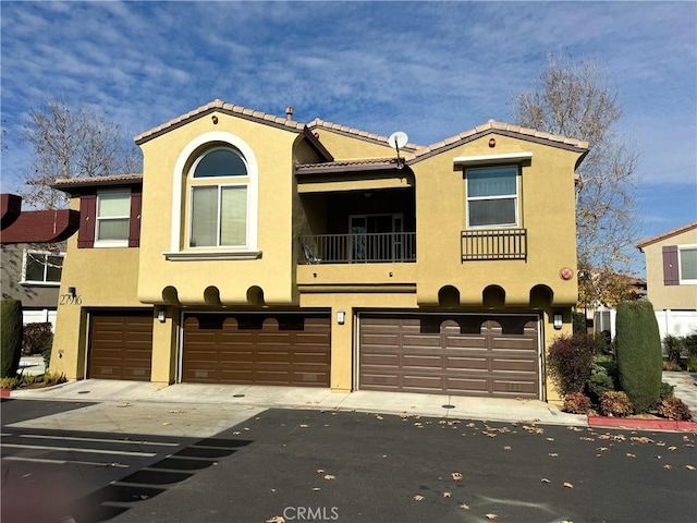 mediterranean / spanish-style house featuring a garage, driveway, a tile roof, and stucco siding