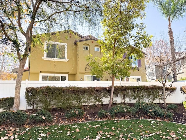 mediterranean / spanish home with fence and stucco siding