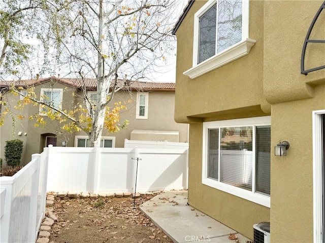 view of home's exterior with cooling unit, fence, a tile roof, and stucco siding