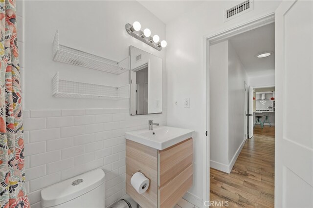 bathroom with vanity, wood-type flooring, tile walls, and toilet