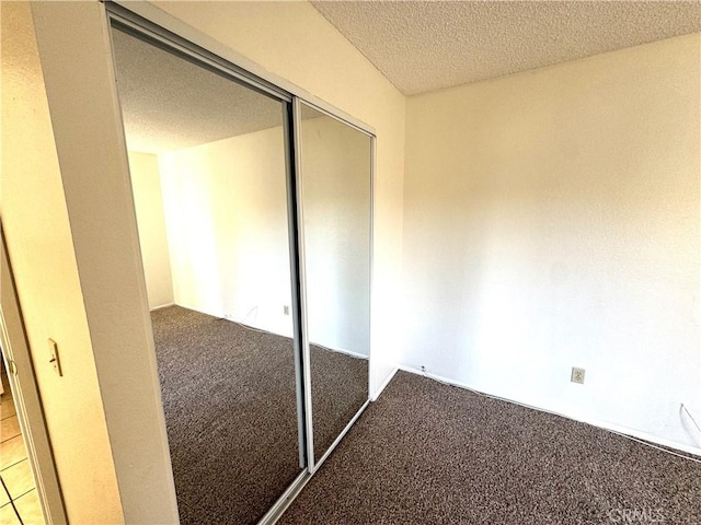 unfurnished bedroom featuring a closet, carpet floors, and a textured ceiling