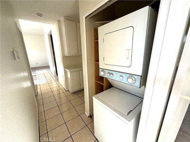 washroom featuring light tile patterned floors, a textured ceiling, and stacked washer and clothes dryer