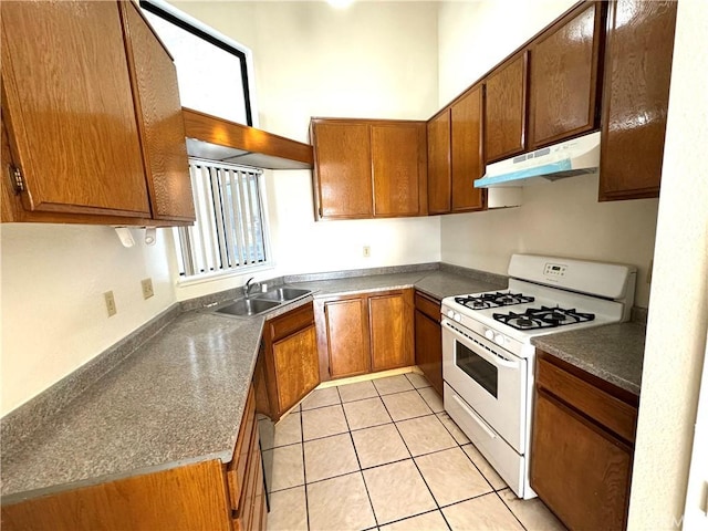 72 Brownfield Ln, Pomona, CA 91766 - kitchen featuring under cabinet range hood, white gas range oven, a sink, and dark countertops