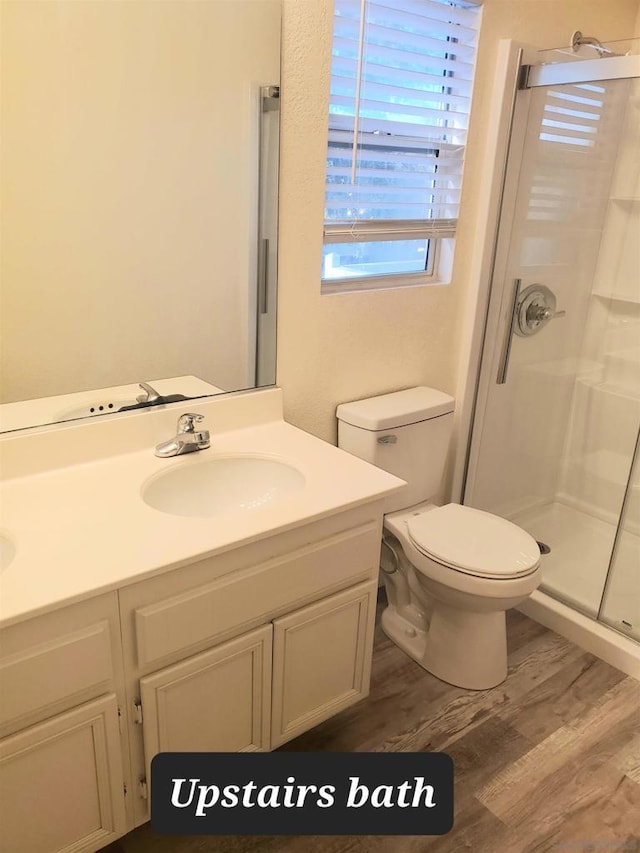 bathroom featuring hardwood / wood-style floors, vanity, toilet, and walk in shower