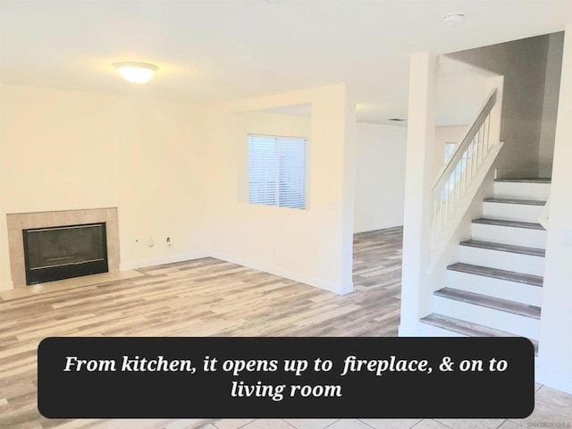 unfurnished living room with a tile fireplace, wood-type flooring, and a wealth of natural light