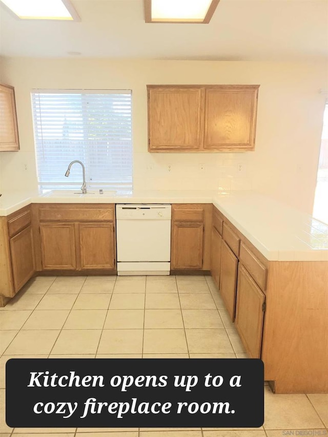 kitchen featuring kitchen peninsula, dishwasher, light tile patterned floors, and sink