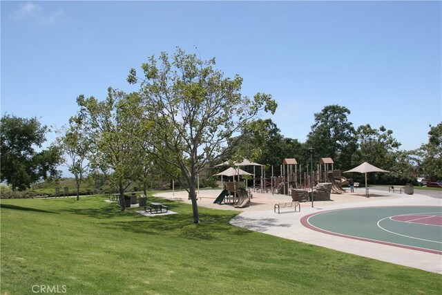 view of home's community with basketball hoop, a playground, and a lawn