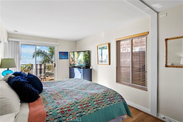 bedroom with access to exterior, wood-type flooring, and multiple windows