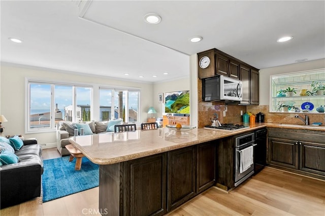 kitchen featuring decorative backsplash, appliances with stainless steel finishes, kitchen peninsula, sink, and light hardwood / wood-style floors