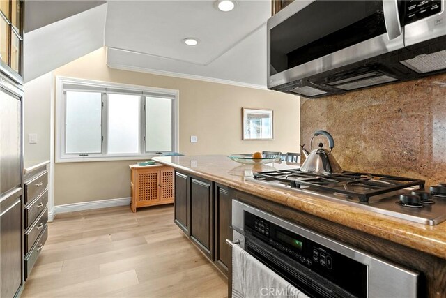 kitchen with backsplash, crown molding, dark brown cabinets, light hardwood / wood-style floors, and stainless steel appliances