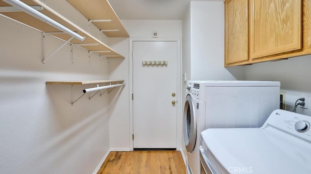 laundry area featuring cabinets, separate washer and dryer, and light hardwood / wood-style flooring