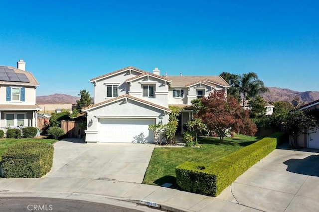 front of property with a mountain view, a front yard, and a garage