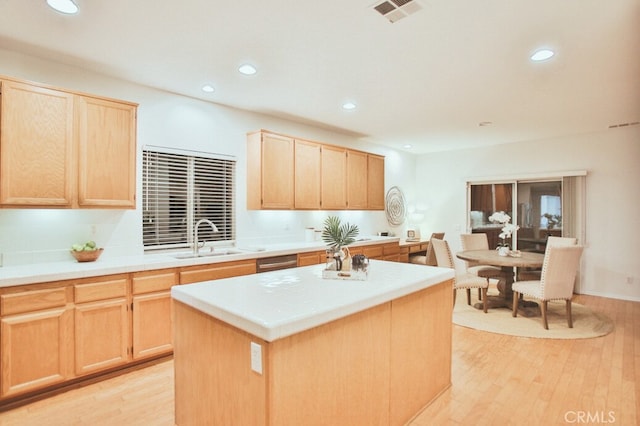 kitchen with light wood-type flooring, light brown cabinetry, sink, and a center island