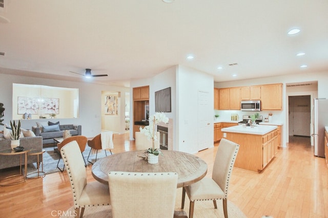 dining space with ceiling fan and light wood-type flooring