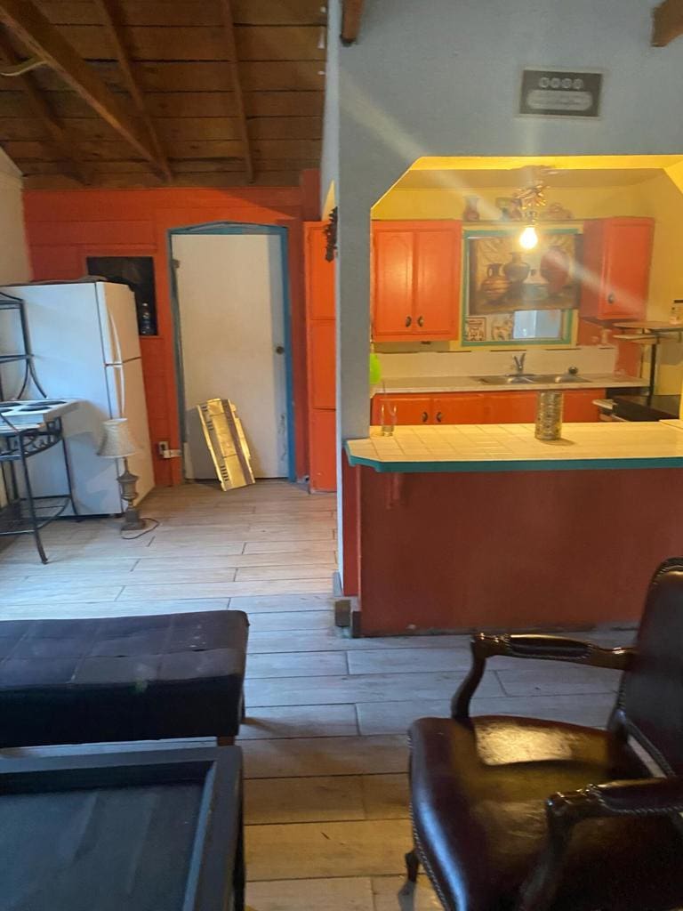 kitchen with beam ceiling, white refrigerator, light wood-type flooring, and sink