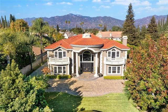 back of house with a mountain view, a yard, and a balcony