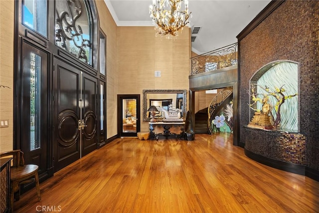 foyer with hardwood / wood-style floors, crown molding, and an inviting chandelier