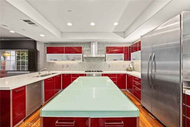 kitchen featuring sink, a kitchen island, wall chimney range hood, and appliances with stainless steel finishes