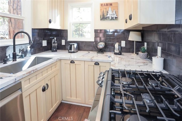 kitchen featuring backsplash, stainless steel appliances, dark wood-type flooring, sink, and cream cabinetry