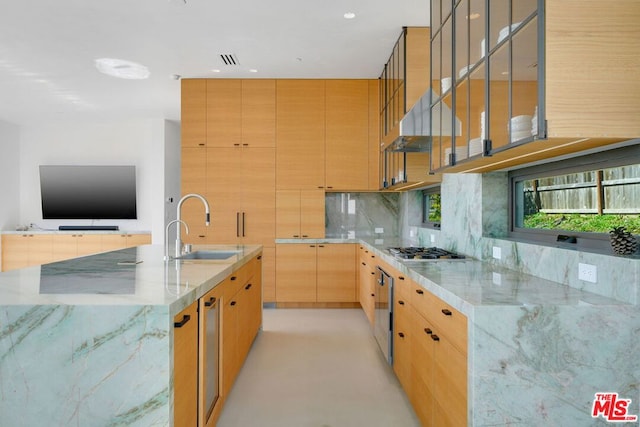 kitchen featuring light stone counters, stainless steel gas stovetop, a large island, and sink