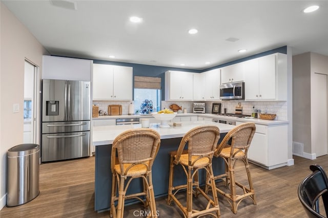 kitchen with a center island, hardwood / wood-style floors, white cabinets, and stainless steel appliances