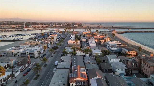 aerial view at dusk with a water view and a beach view