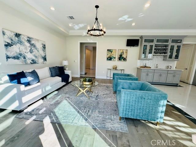 living room with hardwood / wood-style floors, ornamental molding, and an inviting chandelier