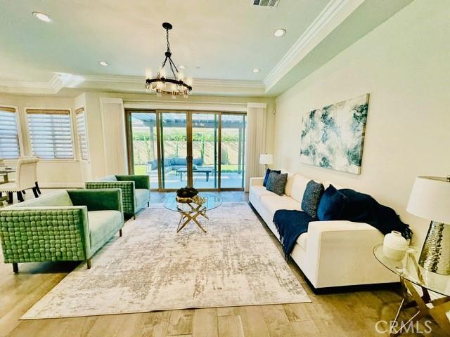 living room featuring light hardwood / wood-style flooring, a notable chandelier, and ornamental molding